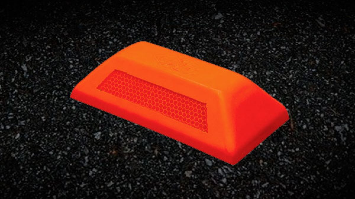 Tachón desmontable de poliuretano de color naranja en una zona de construcción temporal en Lima, mostrando su base de anclaje. Diseño de **tachones desmontables para proyectos de obra.